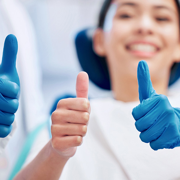lady in dental chair with thumbs up smiling