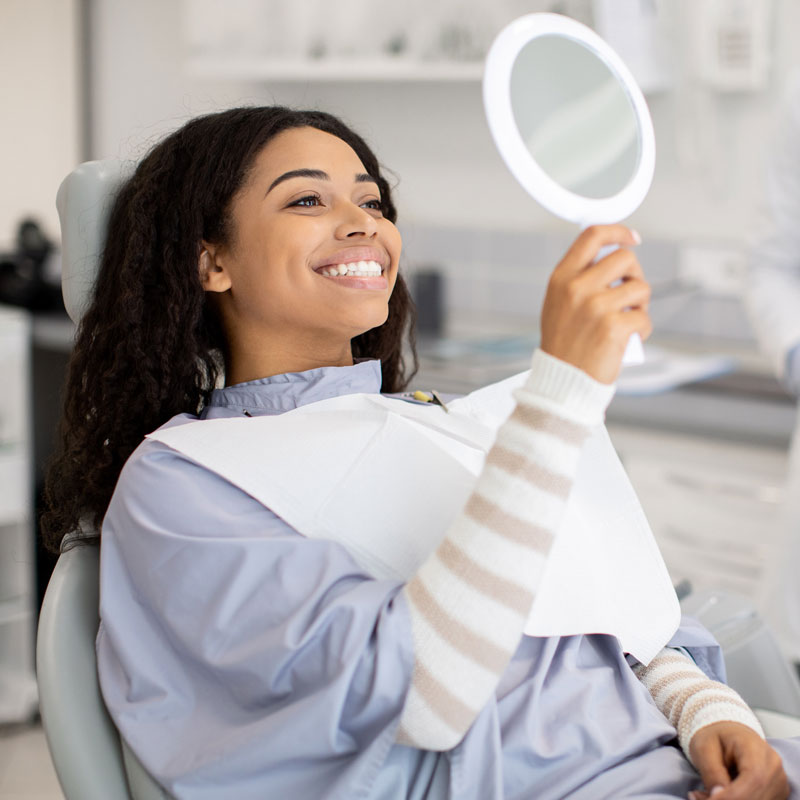 lady holding a mirror while smiling