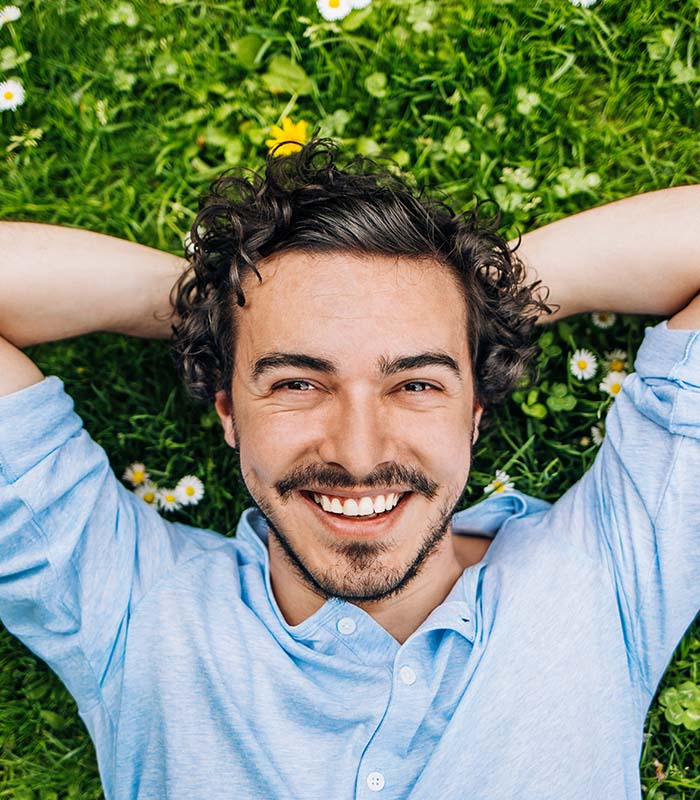 Young man laying on the grass and smiling